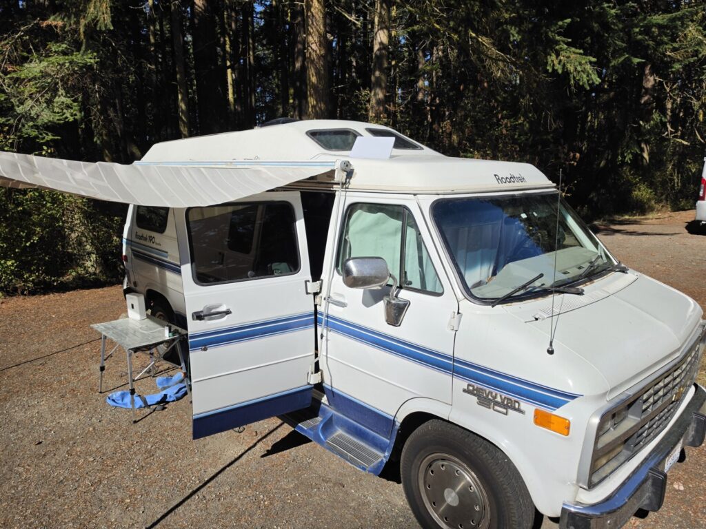 1995 Roadtrek 190 Versatile parked under fir trees at Fort Worden State Park with a Starlink Mini on the roof