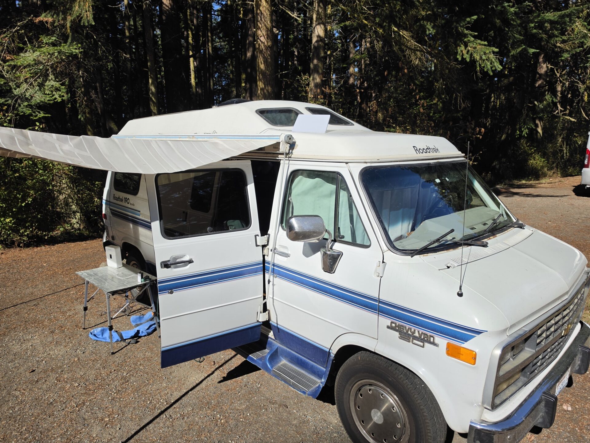 1995 Roadtrek 190 Versatile parked under fir trees at Fort Worden State Park with a Starlink Mini on the roof